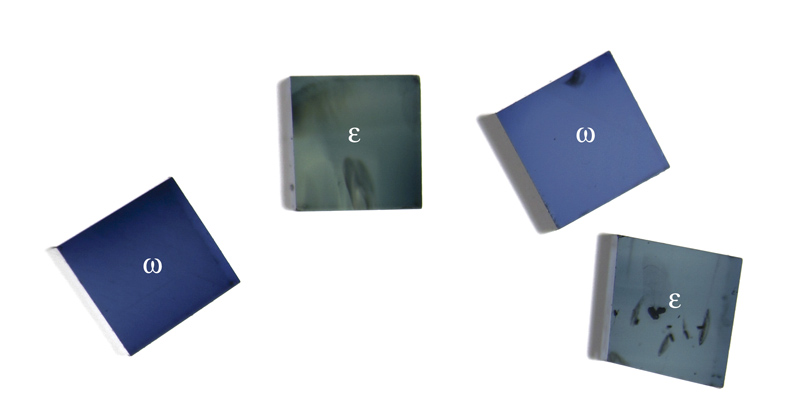 Figure 15. Small cubes of blue sapphire while viewed perpendicular to the optic axis through a polarizing filter. Rotating either the gems or polarizer will switch the two pleochroic colors of each piece. Photo: Wimon Manorotkul
