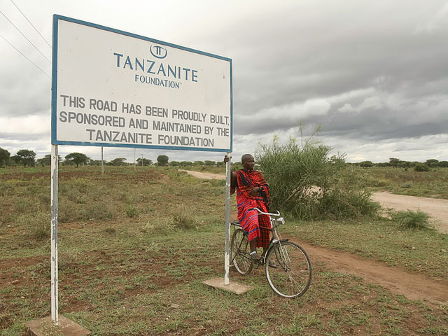 A Masai next to the sign and road to Merelani. Photo: Tanzanite Foundation