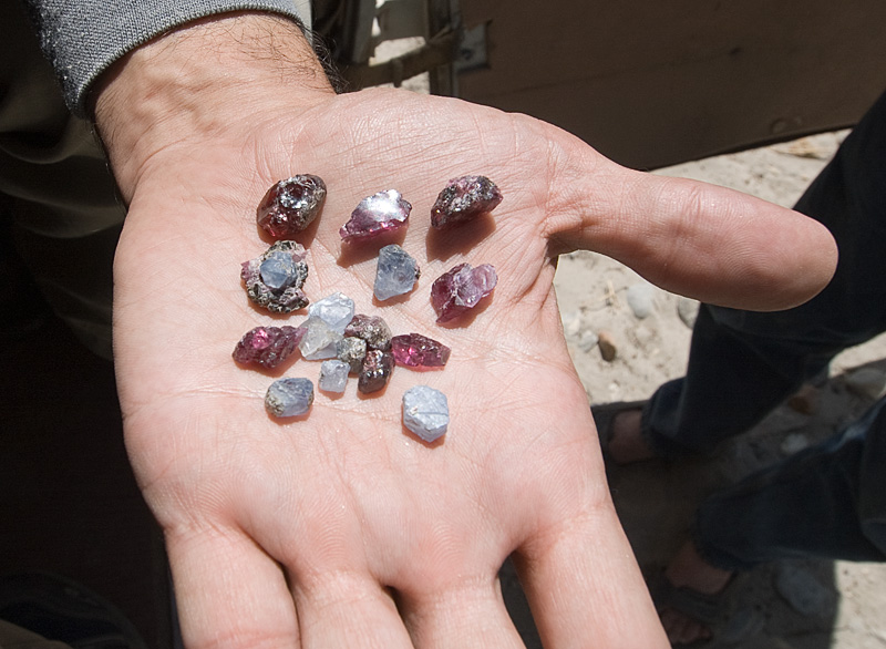 A handful of sapphire and garnet crystals offered to us in the Wakhan Corridor, including one on matrix. Photo: Richard W. Hughes