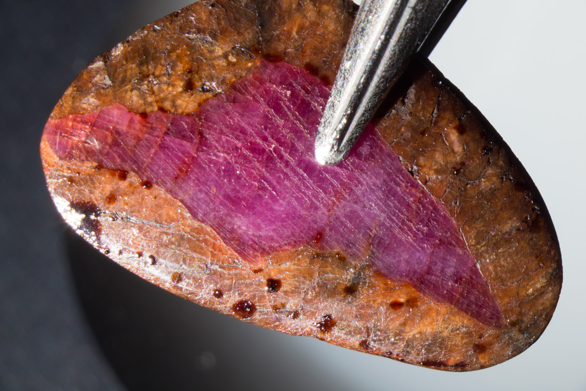 This unusual overgrowth of spinel on ruby was placed by its owner into an oven and gently heated, causing a brown filler to ooze out of the fissures.