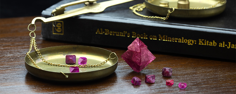 Ruby and spinel crystals, along with al-Biruni's book on precious stones