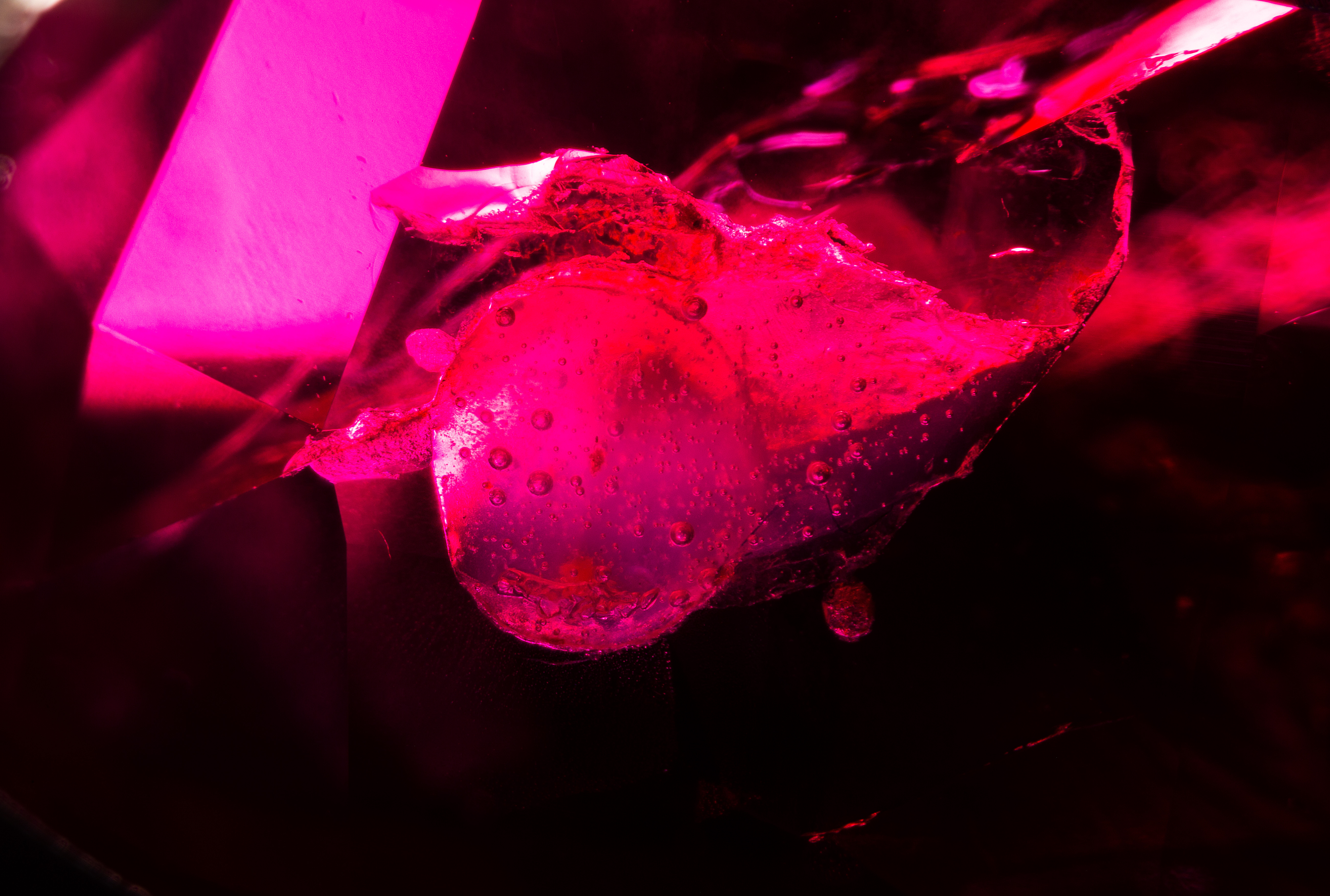 This ruby contains a surface reaching cavity that appears to contain hardened resin, depicted here with dark field illumination.