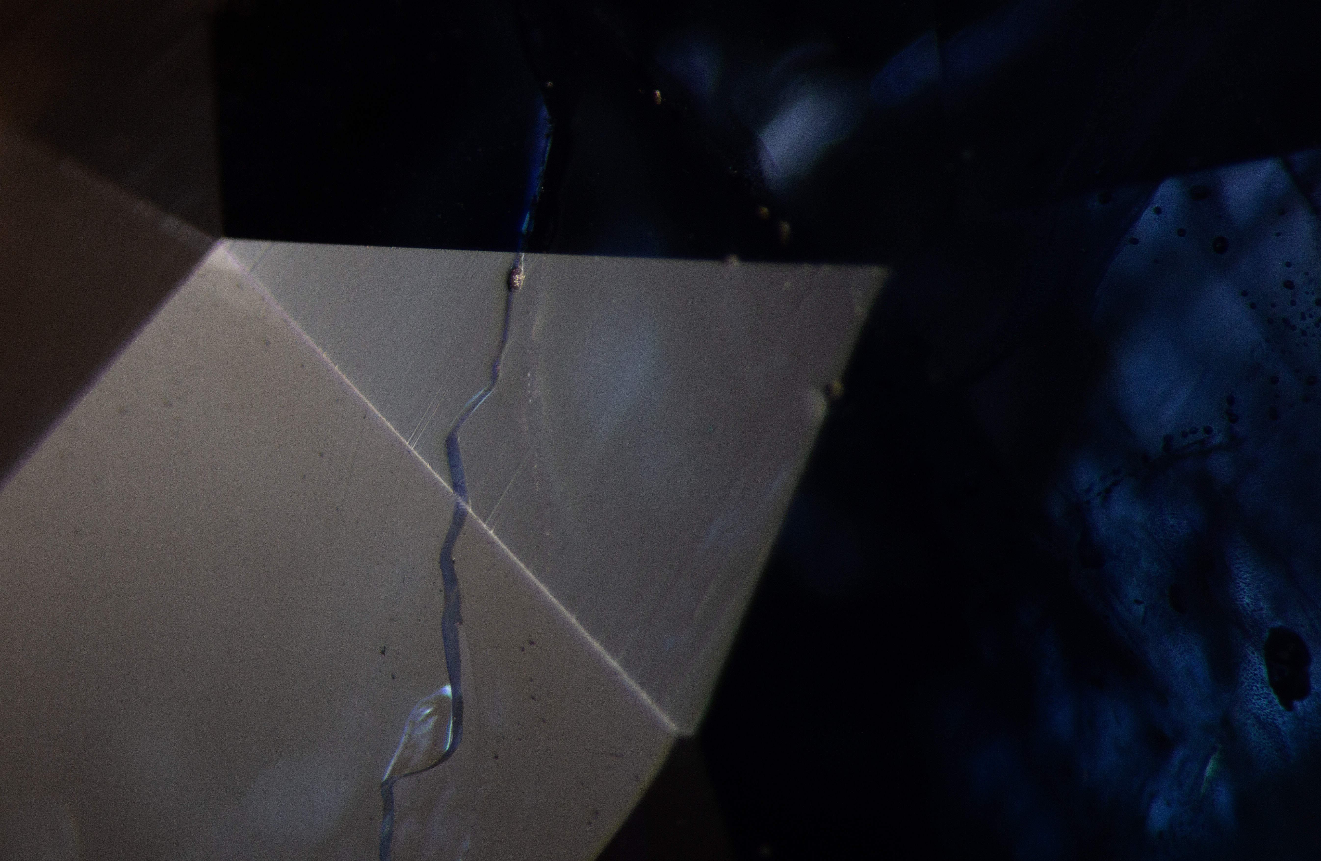 Using a diffuse reflected fiber optic light, a fissure can be observed in this sapphire. Note the lower luster on the surface of the fissure, a sign of glass filling. While it is important to examine the surface with reflected light to detect glass filling, sometimes this can be hard to see if the fissure is very fine.