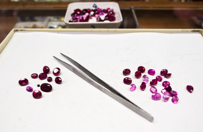 The stones above were from a mixed parcel of synthetic ruby (in the tray at the back). The stones to the right of the tweezers tested accurately, while the stones to the left did not. One can see that the stones that tested accurately tend to be of lighter to medium color, while the stones that had problems were darker and include those of very small size. 