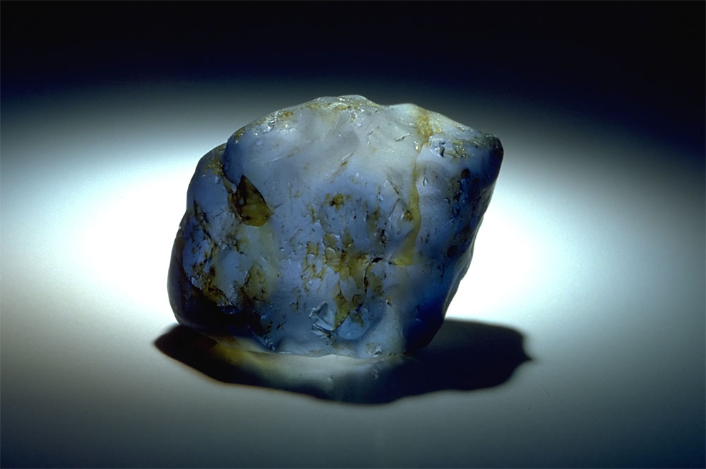 Top: Verneuil synthetic blue sapphire rough which has been tumbled, fractured and stained yellow to resemble natural rough.