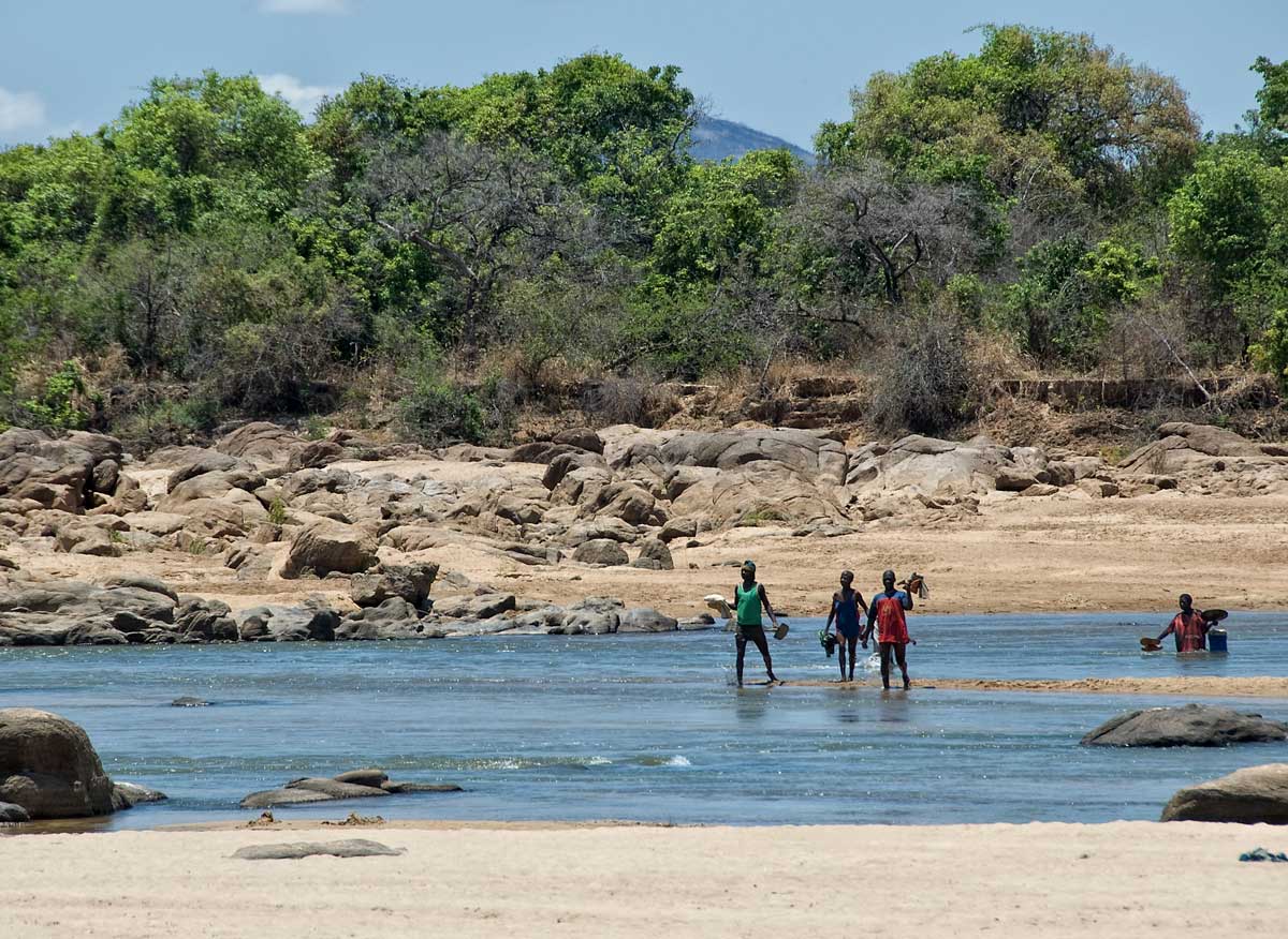 Miners fording the Ruvuma river that separates Tanzania (near bank) from Mozambique (far bank), in Tanzania's Tunduru district. Gems are found on both sides of the river. Photo: Richard W. Hughes