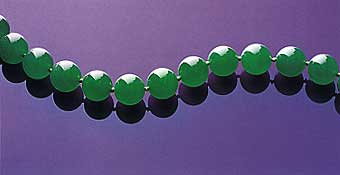 Figure 25. Uniformity of a fine "emerald" green color, superb translucency, size, and symmetry all come together to produce the necklace known as the Doubly Fortunate. The 27 beads, which range from 15.09–15.84 mm, were all cut from the same piece of rough, a 1 kg portion of a much larger boulder. The name derived from the fact that the necklace's owners "doubled their fortunes" every time the boulder was cut (Christie's, 1997, p. 70). The necklace sold in 1997 for approximately US$9.3 million. Photo courtesy of and © Christie's Hong Kong and Tino Hammid.