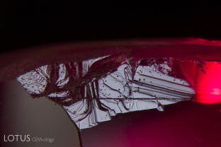 A small “natural” is found on the pavilion of this ruby from Montepuez, Mozambique. Naturals are small traces of the original crystal surface. This one shows tiny triangular pits and stepped “oscillatory” growth.