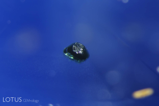 An unusual green crystal was found trapped in this unheated blue sapphire from Serendib.