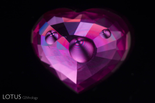 When drops of di-iodomethane are placed on the surface of this rather shallow Mozambique ruby and it is examined between crossed polars, small uniaxial interference figures are readily resolved.