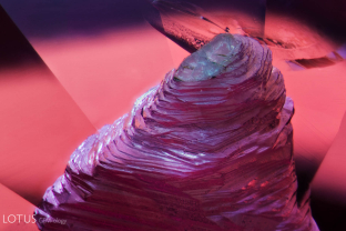 Like a terraced mountain, this large negative crystal rises in the center of an untreated padparadscha sapphire from Sri Lanka.