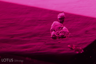 Unusual negative crystal with black flakes adhering to it in a ruby from Tajikistan’s Snijnie mines.