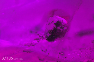 Unusual negative crystal with black flakes adhering to it in a ruby from Tajikistan’s Snijnie mines.