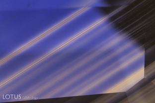 This image clearly illustrates what master photomicrographer John Koivula has termed “chromophore cannibalization.” As titanium is drawn out of solid solution to form exsolved rutile silk, the area in the vicinity is decolorized, losing its blue color. This is a natural process and is the reverse of “internal diffusion,” where heat treatment sends the titanium back into solution, creating blue clouds or “inkspots” around the rutile remnants.