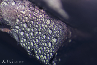 Etch marks of the surface of a natural on a sapphire from Myanmar’s Mogok Stone Tract. The symmetry of the etch marks reveals the underlying atomic symmetry.
