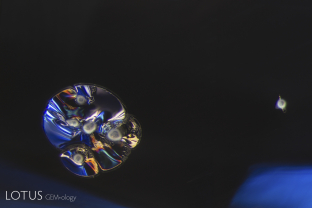 This cluster of melted crystals with a frosty “snowball” appearance and glassy discoid around them is a clear sign that their sapphire host has been heat treated.