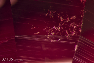 Magnification of this beryllium-diffused orange sapphire reveals small areas on the surface where corundum has melted and recrystallized. This is sometimes seen in beryllium-diffused corundums, due to the high temperatures reached during the treatment.