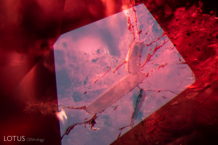 This dolomite crystal cut through on the surface of its spinel host contains black graphite flakes. These inclusions were identified with micro Raman.