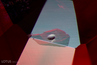 A glass filled cavity is visible on the surface of this ruby. The rounded indentation is an area where a gas bubble was cut through.