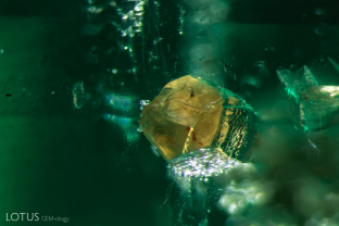 This angular yellow stood out immediately when we examined this ermerald. Analysis with micro Raman revealed that it is parisite.