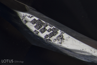 In the “We thought we had seen it all” department, this unusual inclusion was found on the polished girdle of an untreated Madagascar sapphire. We believe it to be made up of growth marks on the surface of the original sapphire crystal.