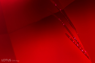 Transparent rod-like crystals peek out from behind a facet edge in this Mozambique ruby. While micro Raman analysis did not conclusively identify these rods, from they are likely amphibole based on their appearance.