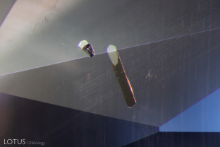 Two types of rutile can be viewed in t his inclusion scene: fine rutile “silk” needles and the dark brownish primary rutile crystal present in the foreground. The primary rutile was identified with micro Raman. Note that when illuminated with reflected light the primary rutile shows an extremely high luster where cut through on the surface.
