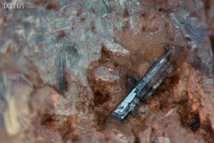 This piece of Kashmir sapphire rough we examined had an interesting elongated, prismatic crystal attached to the surface. Analysis with micro Raman identified it as tourmaline.