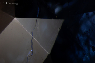 When observed with diffuse reflected illumination from a fiber optic light guide, the surface of this sapphire shows a glass filled fissure of lower luster.