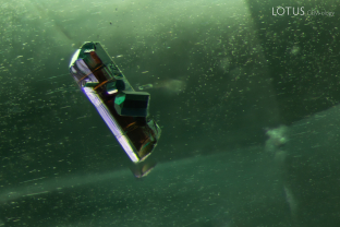 A brown, prismatic crystal, possibly tourmaline, is suspended inside of this schist-hosted emerald.