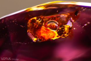A small cavity containing a mobile bubble can be observed under magnification in this spinel. Raman spectroscopy confirmed that the yellow-orange areas are sulfur-rich fluids. Sample courtesy Rosway.