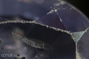 Abraded facet junctions on an untreated Sri Lanka sapphire. According to Robert Webster’s “Gems” (1st edition, 1962, p. 66): “Corundum is a hard stone, indeed the impure material is used as an abrasive, and is rated 9 on the scale of hardness devised by F. Mohs. Despite the hardness of the mineral, however, ruby and sapphire need to be handled with some care, for they are to a slight extent brittle and if dropped on a hard surface or given a sharp blow tend to develop internal flaws and cracks.”