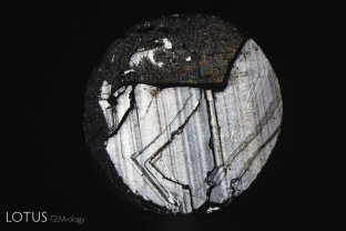 Basal parting seen on the back of a black star sapphire from Chanthaburi, Thailand. Note the step-like appearance. Basal parting in these stones is due to exsolution of hematite/ilmenite silk, which produces both the star effect and a lack adhesion.