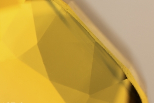 Green color zone in a yellow sapphire from Chanthaburi, Thailand. This type of zoning is typically found on the skin of the crystal and thus after cutting, is generally found just under the table and/or culet. Careful examination often reveals thin patches of iron-rich silk in these green zones.