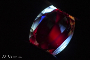 This bright orange sapphire shows no evidence of heat treatment in the microscope, but the chalky zoned shortwave ultraviolet fluorescence quickly unmasks the fact that the stone had been heated.