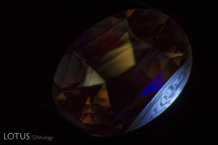 This bright orange sapphire shows no evidence of heat treatment in the microscope, but the chalky zoned shortwave ultraviolet fluorescence quickly unmasks the fact that the stone had been heated.