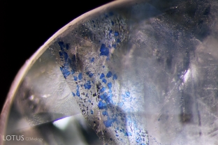 This pale sapphire has been soaked in blue dye to deepen its color. Under the microscope one can clearly see the blue stains in the fissures.