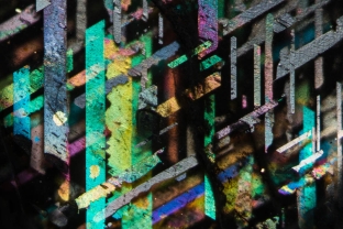 Magnetite (black) and hematite (colored) plates in a “rainbow lattice” feldspar from the Rainbow Serpent Mine, in the Harts Range Northeast of Alice Springs, Northern Territory, Australia. This photomicrograph was a finalist in the Close Up Photographer of the Year competition. <https://www.cupoty.com/the-top-100>